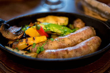 Grilled fried sausages kupaty on iron skillet grill with vegetables