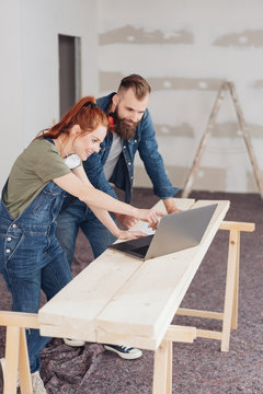 Young couple pointing to laptop during renovations