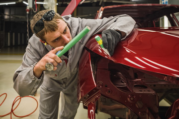 Fototapeta na wymiar Employee car body painting shop eliminates a small metal defect