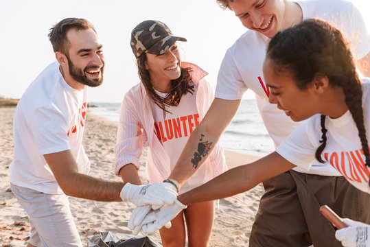 Image of smiling teamwork volunteers holding hands together