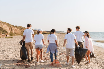 Image from back of multinational young volunteers cleaning beach