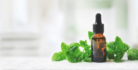 aromatherapy treatment - essential oil bottle with mint leaves on clean bright background with copy...