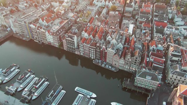 Aerial Drone Shot of the famous houses lining the edge of the Damrak canal basin, Amsterdam, Netherlands in the early morning