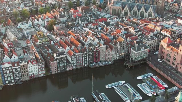 Aerial Drone Shot of the famous houses lining the edge of the Damrak canal basin, Amsterdam, Netherlands in the early morning