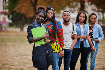 Row of group five african college students spending time together on campus at university yard....