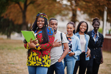 Row of group five african college students spending time together on campus at university yard....