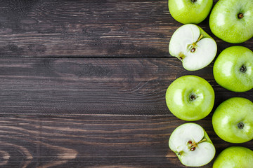 Ripe green apples and apple slices on old wooden background.Vegetables for diet and healthy eating.Organic food. Place for text. Top view