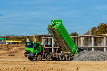 Construction truck tipping dumping gravel on road construction site,tip truck and ripper at work...