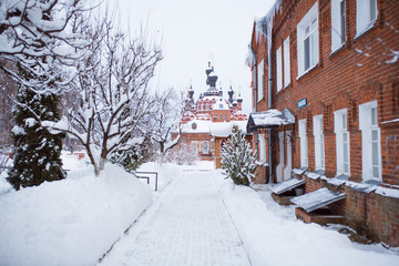 Convent of the Kaluga virgin Mary in winter.  Wooden Christian Church in Shamordino in the snow, alley and bells near the Church