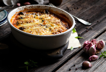 baked eggplant rolls with tomato sauce, melted cheese in white ceramic oval baking pan
