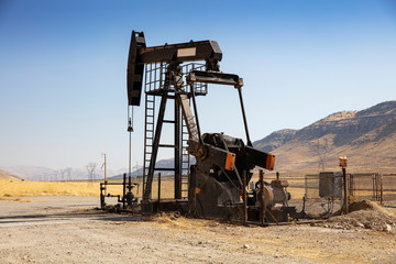Oil drilling derricks at desert oilfield. Crude oil production from the ground. Oilfield services contractor. Oil drill rig and pump jack. Petroleum production, natural gas, liquids, NGL, additive.