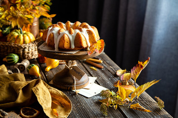 homemade tasty baked bundt pumpkin cake with glaze on top on wooden cake stand