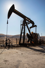 Oil drilling derricks at desert oilfield. Crude oil production from the ground. Oilfield services contractor. Oil drill rig and pump jack. Petroleum production, natural gas, liquids, NGL, additive.