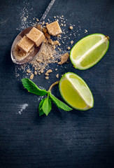 Ingredients for Mojito cocktail-mint, lime, cane sugar on a dark wooden background. Copy space