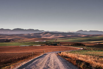 Fototapeta na wymiar Farm road with mountains in the background