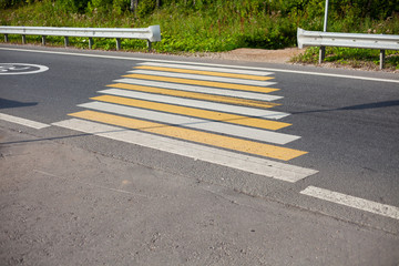 Pedestrian crossing over the transport road. Pedestrian traffic safety through the roadway. Zebra on the asphalt is applied with bella and yellow paint.