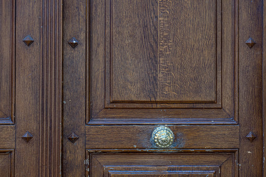 Old wooden door. Dark wood patterned door panel with shiny vintage round doorknob. Architectural details of Paris door of antique building in France. Rough wooden texture