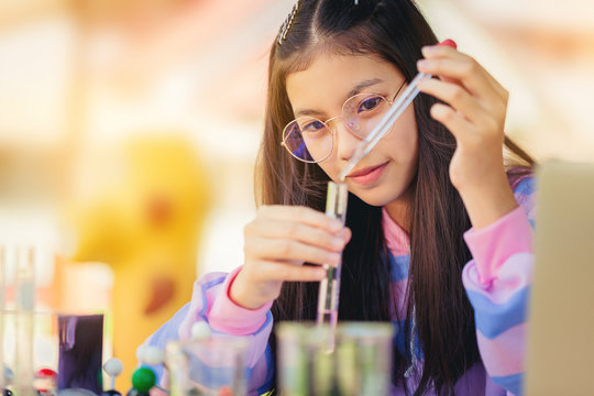 Asian Teenage Girl In Elementary Science Class Doing Chemical Experiment Test Try To Drop Color Water To Test Tubes. Education Concept