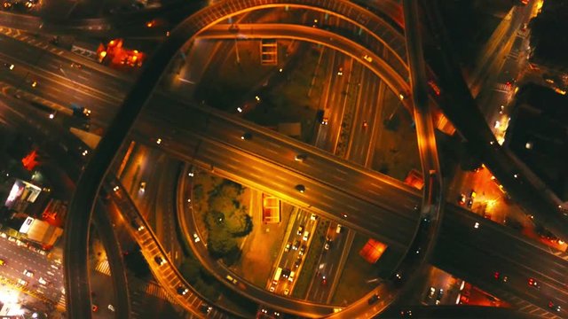 drone footage from a Highway crossing in Buenos Aires, at night. Nice contrast of street lights and shadows. Traffic moving. Slightly out of focus camera effect. Flying upwards.