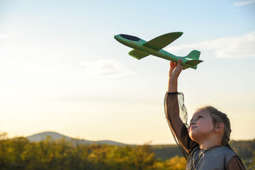 Child pilot aviator with airplane dreams of traveling in summer in nature at sunset children...