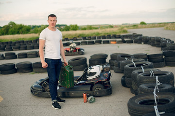 Karting. Man in a white t-shirt. Male refills a car