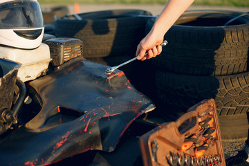 Karting. Man in a white t-shirt. Male repairs the car with a tools