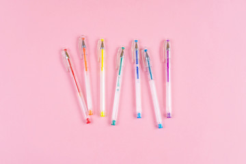 Gel pens of rainbow colors on a pink background. Place for text, minimalism. The concept of school...