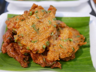 Close up of pieces of Thai fish cake (Tod Mun Pla) on a Banana leaf for sale at a local market in Thailand