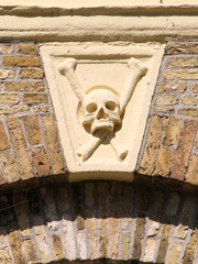 Totenkopf mit gekreuzten Knochen als Detail über einer alten Tür - 298018944