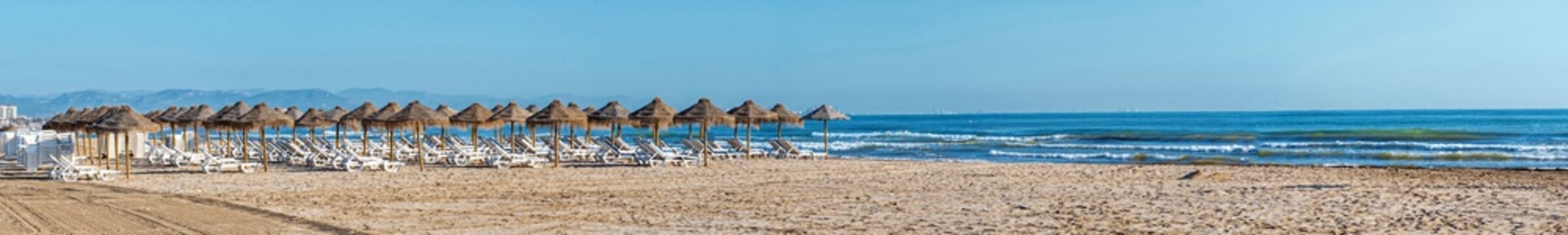 Panoramic view of straw umbrellas and beach loungers on Malvarrosa sand beach in Valencia
