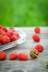   Pink fresh raspberries on an glass vessel on a gray wood background in the garden on the background of green grass Berry Fruit Sadovina Healthy Food hack close up
