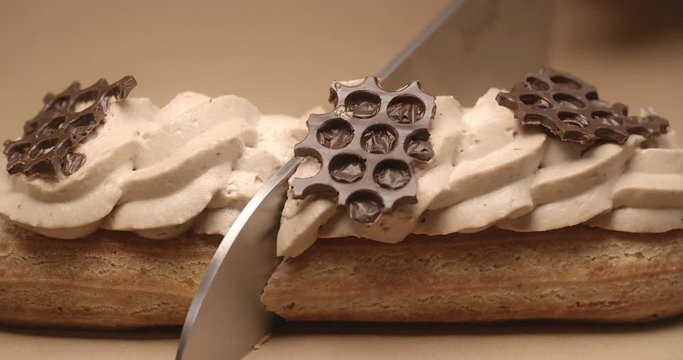 Confectioner cuts eclair in a half by knife in slow motion, dessert in cafe, stuffing for eclairs, choux pastry, 4k DCI 120fps Prores 422 HQ 10 bit