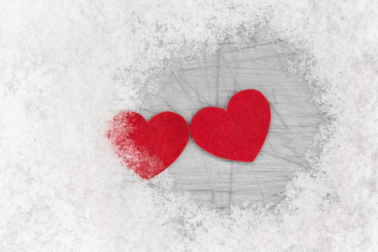 Two red hearts is laying together among snow. Relations concept