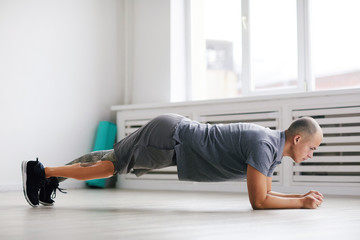 Young disabled man in sports clothing doing push-ups during sports training in the gym