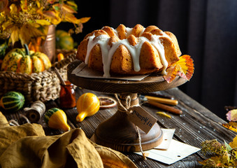 homemade tasty baked bundt pumpkin cake with glaze on top on wooden cake stand