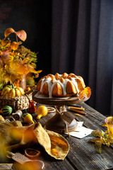 homemade tasty baked bundt pumpkin cake with glaze on top on wooden cake stand