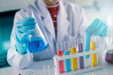 Fototapeta premium Young Asian medical technologist female making testing with test tube while doing research in science laboratory