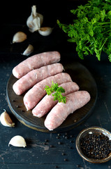 Raw homemade sausages on a wooden cutting board on a dark wooden background