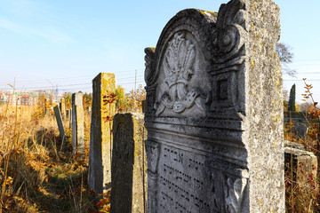 An old cluttered Jewish cemetery with uneven tombstones carved in Hebrew is a preserved story.