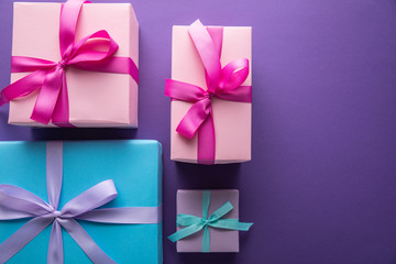 top view of colorful gift boxes with ribbons and bows on purple background with copy space