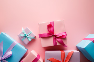 top view of colorful gift boxes with satin ribbons on pink background