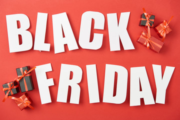 top view of black friday white lettering near small presents on red background