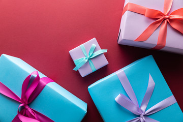 top view of blue and violet gift boxes with ribbons on red background with copy space