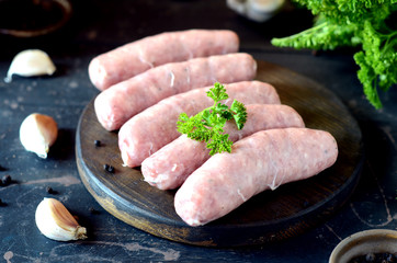 Raw homemade sausages on a wooden cutting board on a dark wooden background