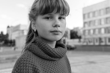 Black and white portrait girl 9-10 years old against the backdrop of the city.