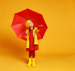 happy emotional cheerful child girl laughing  with red umbrella   on yellow background.