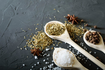  Wooden spoon with Italian seasoning-dried oregano with thyme,vegetables.Oregano in a wooden spoon on a rocky concrete dark black background with a place for text Top view