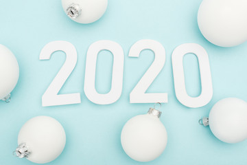 top view of white 2020 numbers near Christmas baubles on light blue background