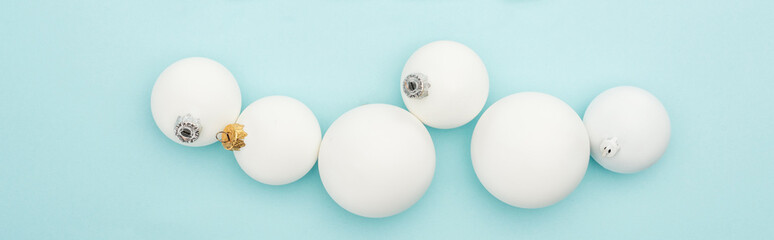 top view of white Christmas baubles on light blue background, panoramic shot