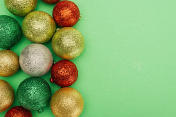 top view of colorful christmas baubles on green background